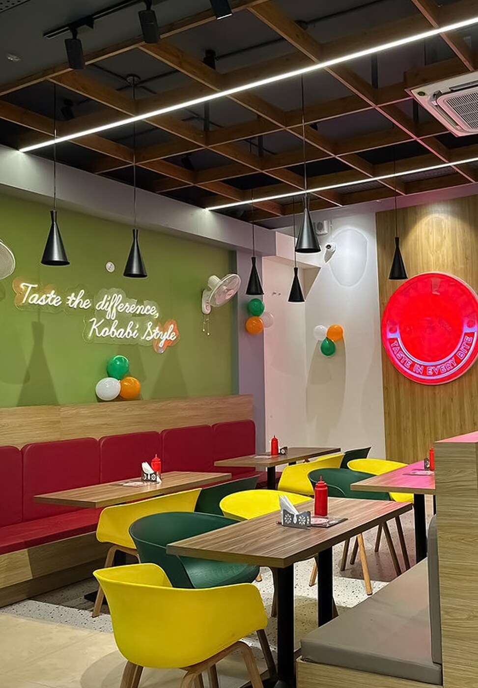 Dining room with booth seating, pendant lights and the neon brand roundel